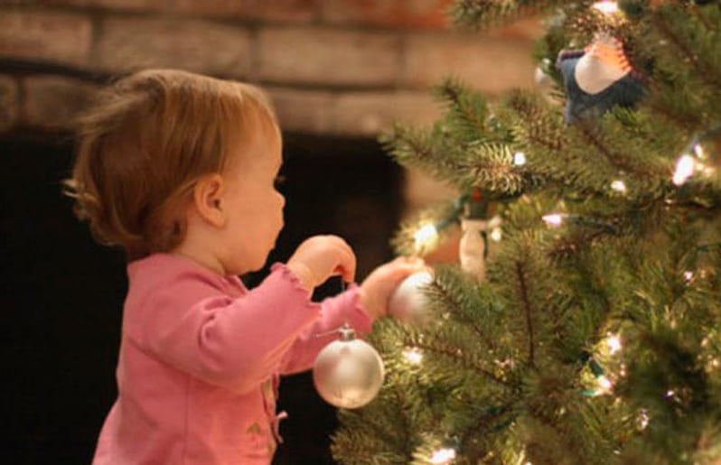 nina jugando en arbol de navidad