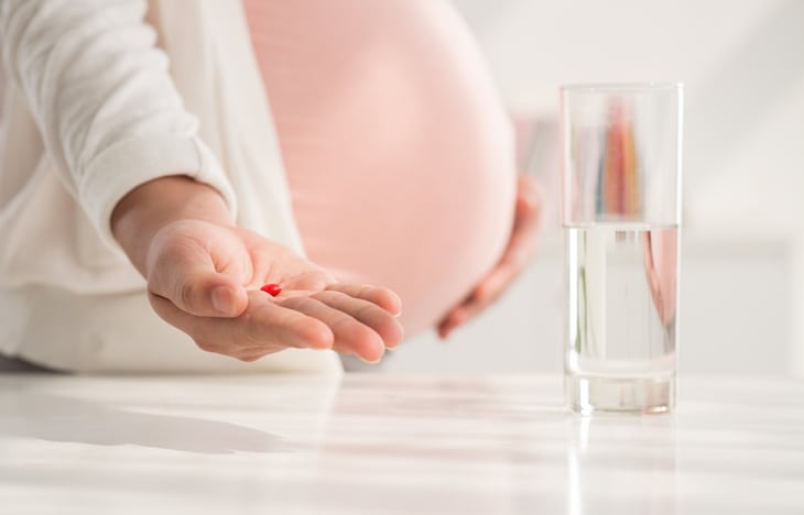 Cropped image of pregnant woman holding a pill