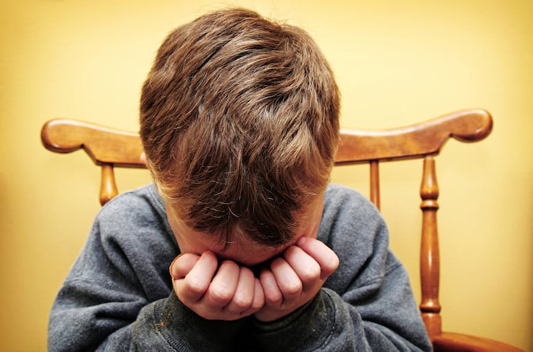 Young boy crying into his hands.  Horizontal with copy space.