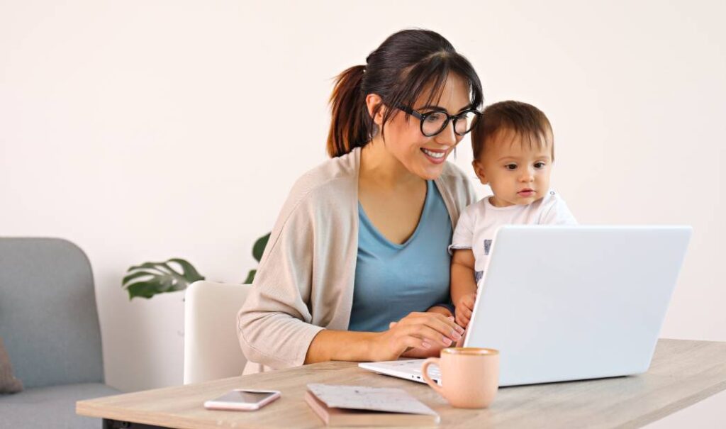 mujer con bebe frente a una computadora